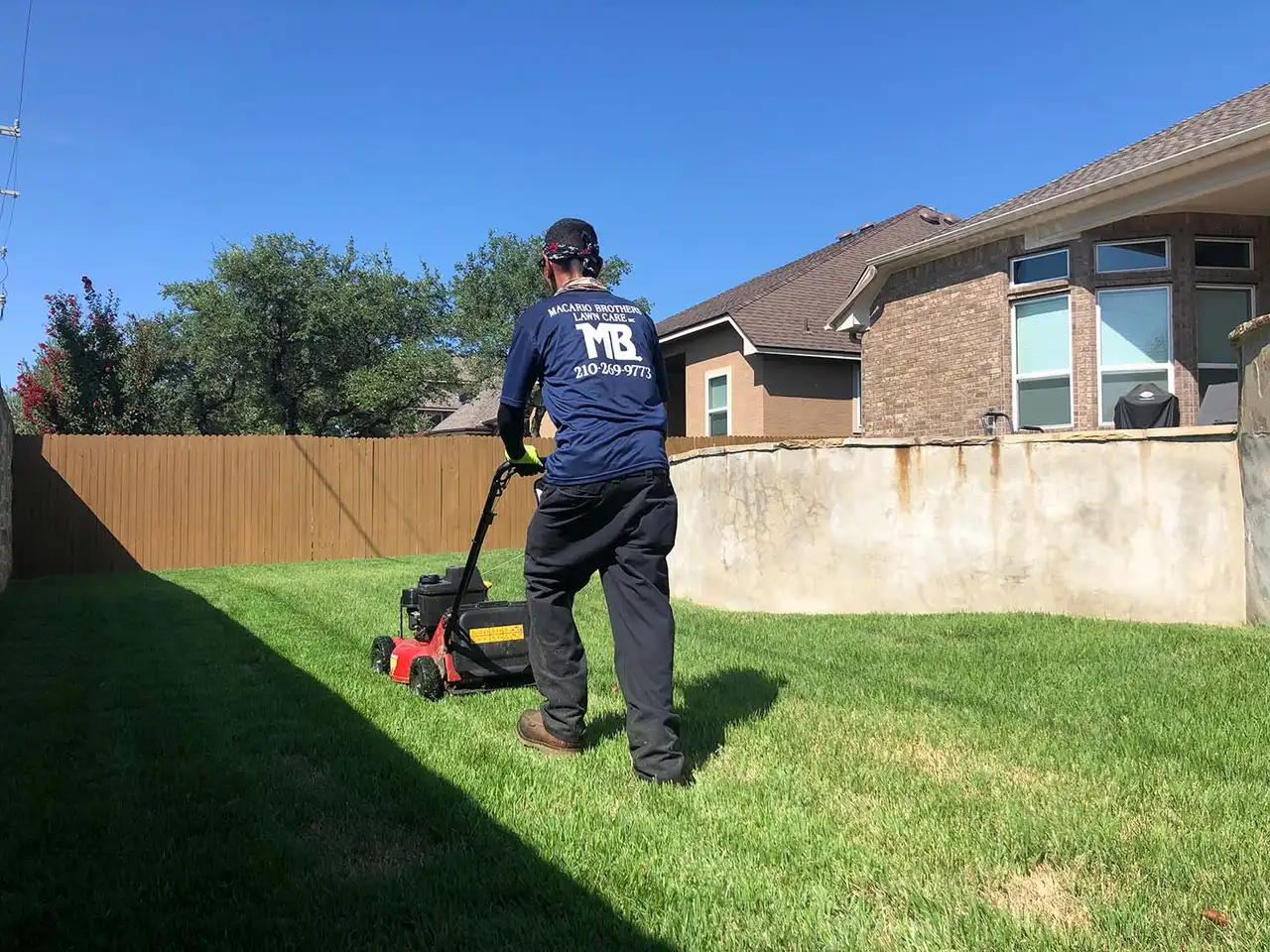 Macario Brothers Lawn Care mowing a San Antonio warm-season lawn on a summer schedule